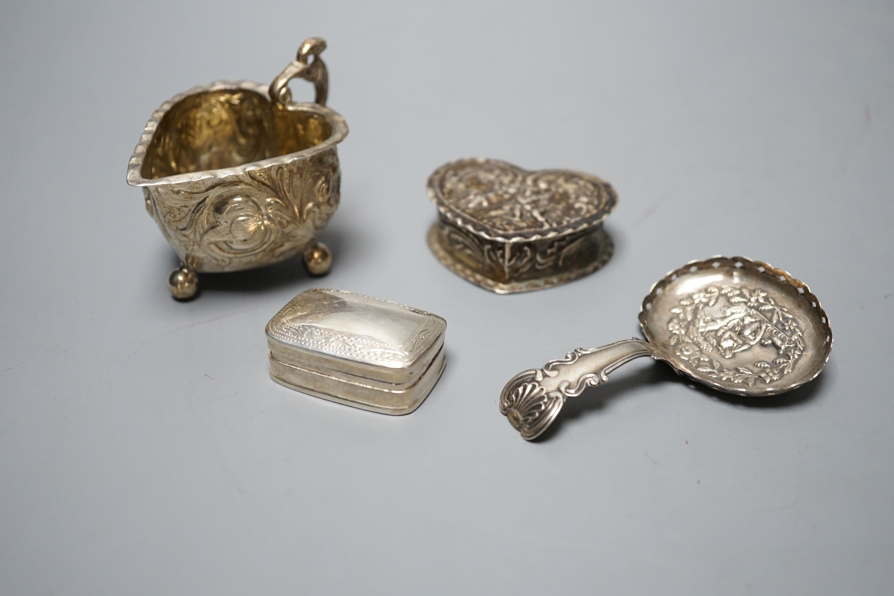 A George III silver caddy spoon, with associated bowl, handle marked for John Bettridge, Birmingham, 1817, 76mm, a late 19thcentury Hanau white metal small jug, an embossed white metal heart shape box and a white metal p